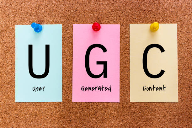 Conceptual 3 letters keyword UGC (User Generated Content) on multicolored stickers attached to a cork board.